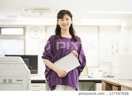 Middle-aged woman working in an office Middle-aged woman working in an office 127487686