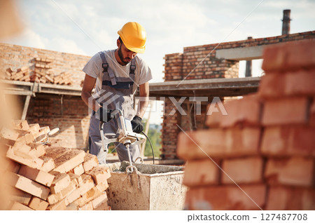 Mixes concrete. Handsome Indian man is on the construction site 127487708