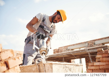 Mixes concrete. Handsome Indian man is on the construction site 127487709