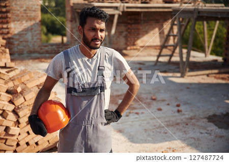 In grey uniform. Handsome Indian man is on the construction site 127487724