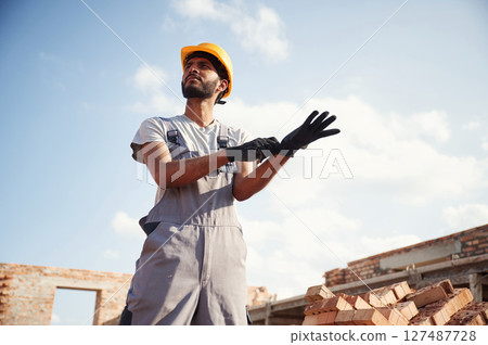 Outdoors at daytime. Handsome Indian man is on the construction site Outdoors at daytime. Handsome Indian man is on the construction site 127487728