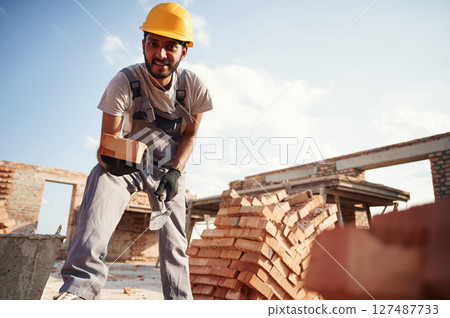 View from below. Brick in hand. Handsome Indian man is on the construction site 127487733