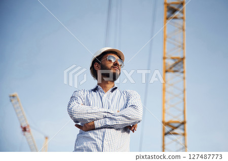 Manager in sunglasses. Handsome Indian man is on the construction site Manager in sunglasses. Handsome Indian man is on the construction site 127487773