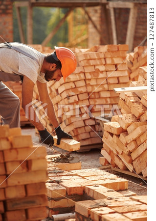 Bunch of bricks. Placing them. Handsome Indian man is on the construction site Bunch of bricks. Placing them. Handsome Indian man is on the construction site 127487813