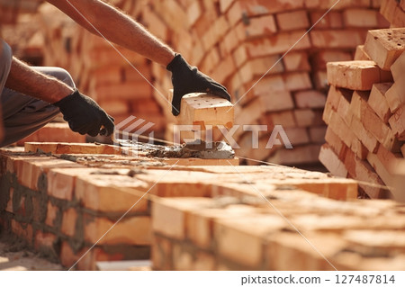 Placing the bricks. Close up view of man that is working on the construction site Placing the bricks. Close up view of man that is working on the construction site 127487814