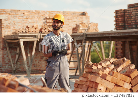 Wearing the gloves. Handsome Indian man is on the construction site Wearing the gloves. Handsome Indian man is on the construction site 127487832