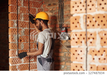 Placing the electricity wires. Handsome Indian man is on the construction site Placing the electricity wires. Handsome Indian man is on the construction site 127487834