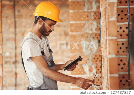 Placing the electricity wires. Handsome Indian man is on the construction site 127487837
