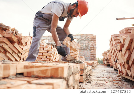 Side view, working and placing the bricks. Handsome Indian man is on the construction site 127487853