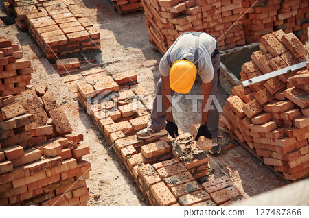 On the top of the building with bricks. Handsome Indian man is on the construction site 127487866
