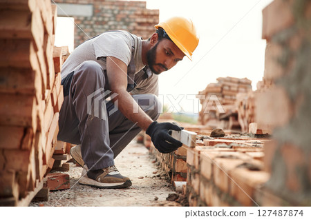 Using the leveler. Handsome Indian man is on the construction site 127487874