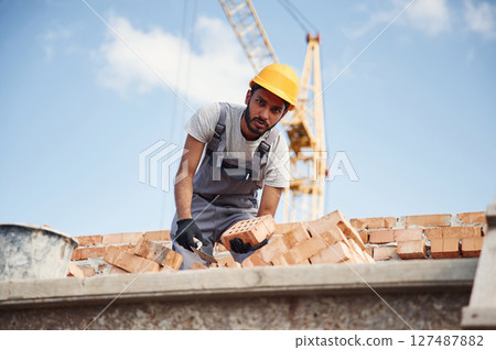 Working against blue sky. Handsome Indian man is on the construction site 127487882