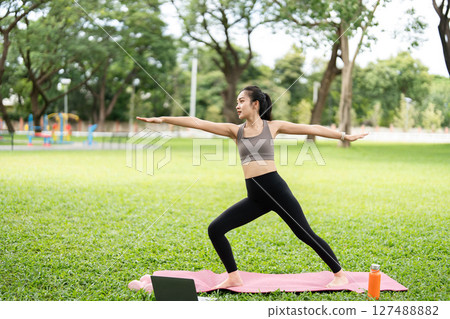 Yoga and wellness. Young woman practicing warrior pose outdoors. 127488882