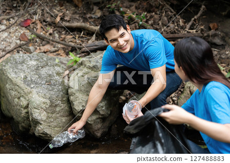 Community Volunteers Collecting Waste Near Stream. Two individuals collaborating on environmental cleanup. 127488883