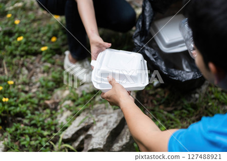 Community Volunteer Action. Two individuals collaborating to remove litter from a natural setting. Community Volunteer Action. Two individuals collaborating to remove litter from a natural setting. 127488921
