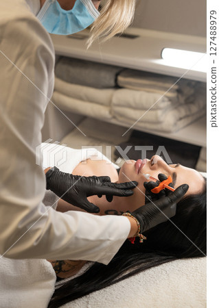 Syringe near woman's chin, beauty injections with fillers for chin shape correction. 127488979