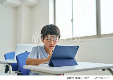 Boy operating a tablet device Boy operating a tablet device 127489252