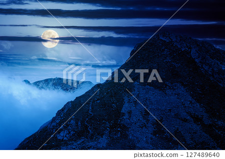 mountain landscape under cloudy sky at night. nature scenery travel background for hiking in summer vacation season in full moon light. scenic view of ridge with steep rocky slopes 127489640