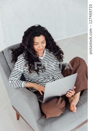Curly sitting on chair with laptop online Curly sitting on chair with laptop online 127489710