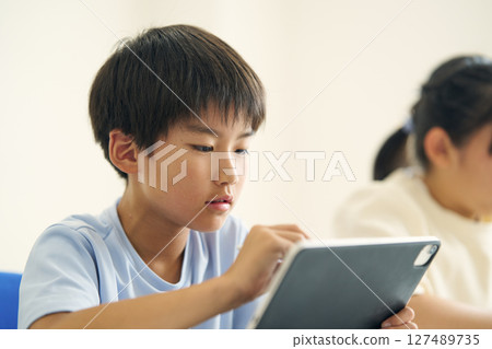 Elementary school student operating a tablet device Elementary school student operating a tablet device 127489735