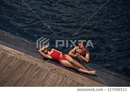 With cocktail. Man with woman is in the pool together 127490511