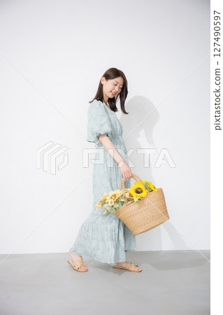 Cute young woman holding a sunflower, looking at the camera, full body, summer fashion and outing image 127490597