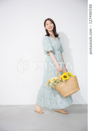 Cute young woman holding a sunflower, looking at the camera, full body, summer fashion and outing image 127490598