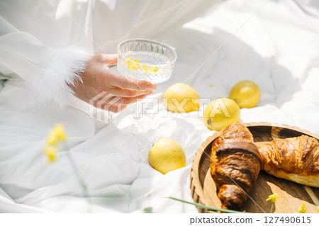 Lovely picnic setup featuring a refreshing drink, croissant, and lemons among spring flowers Lovely picnic setup featuring a refreshing drink, croissant, and lemons among spring flowers 127490615