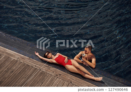With cocktail. Man with woman is in the pool together With cocktail. Man with woman is in the pool together 127490646
