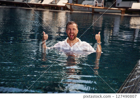 Handsome man in formal clothes is in the pool Handsome man in formal clothes is in the pool 127490807