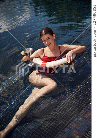 With drink in hand. Young woman in red swimsuit is in the pool With drink in hand. Young woman in red swimsuit is in the pool 127490853