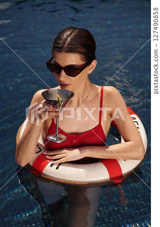 With lifebuoy. Young woman in red swimsuit is in the pool With lifebuoy. Young woman in red swimsuit is in the pool 127490858