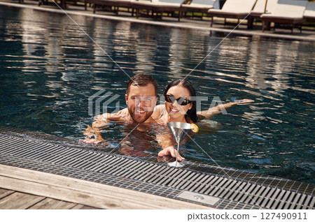 Embracing each other. Man with woman is in the pool together Embracing each other. Man with woman is in the pool together 127490911
