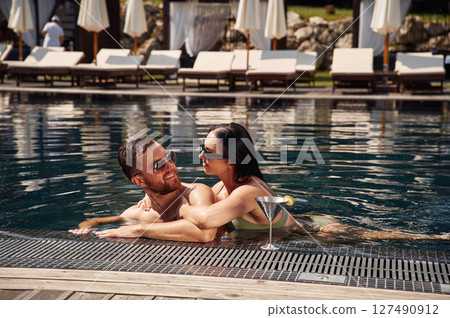 Embracing each other. Man with woman is in the pool together Embracing each other. Man with woman is in the pool together 127490912