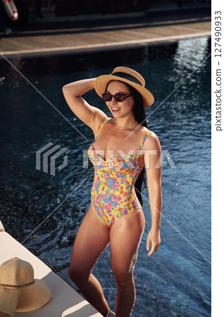 Beautiful woman that is in swimsuit is in the pool Beautiful woman that is in swimsuit is in the pool 127490933