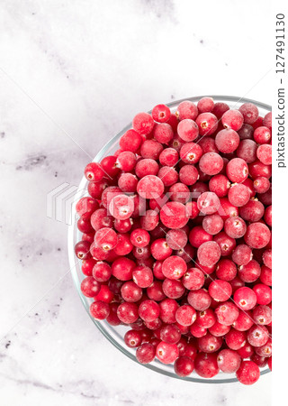 Frozen cranberries in transparent bowl, on light background. Preservation of vegetables and fruits. Natural products Frozen cranberries in transparent bowl, on light background. Preservation of vegetables and fruits. Natural products 127491130