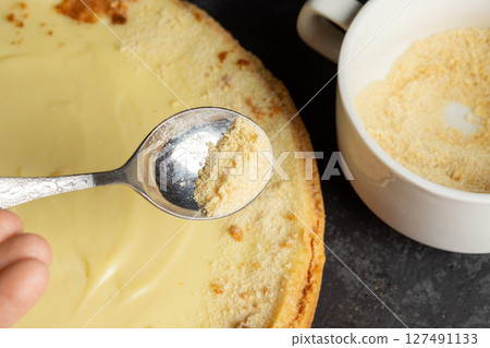 Homemade classic cheesecake on dark background. Decorating delicious cake with cookie crumbs. 127491133