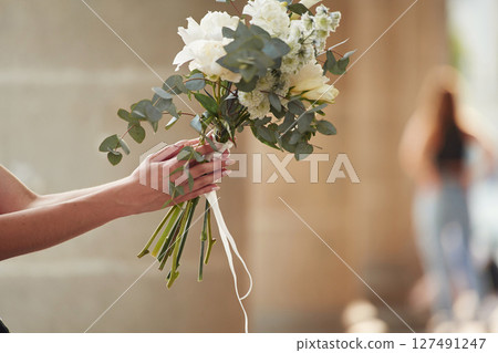 Close up view of flowers in hand. Woman is outdoors 127491247