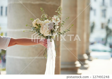 Close up view of flowers in hand. Woman is outdoors 127491248