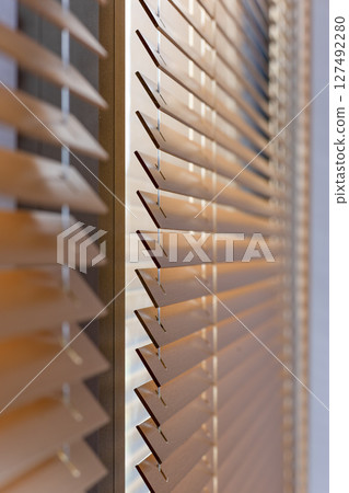 Side View of Angled Wooden Blinds Filtering Sunlight Side View of Angled Wooden Blinds Filtering Sunlight 127492280