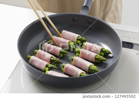 A scene of cooking asparagus bacon in the kitchen A scene of cooking asparagus bacon in the kitchen 127493502