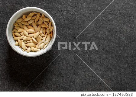 pumpkin seeds on bowl on black background, top view 127493588