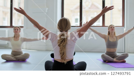 Women practicing yoga sitting in lotus pose meditation relaxing. Sporty women doing exercise in studio for class for yoga wellness mindfulness meditation. Women practicing yoga sitting in lotus pose meditation relaxing. Sporty women doing exercise in studio for class for yoga wellness mindfulness meditation. 127493791