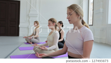 Women practicing yoga sitting in lotus pose meditation relaxing. Sporty women doing exercise in studio for class for yoga wellness mindfulness meditation. Women practicing yoga sitting in lotus pose meditation relaxing. Sporty women doing exercise in studio for class for yoga wellness mindfulness meditation. 127493873