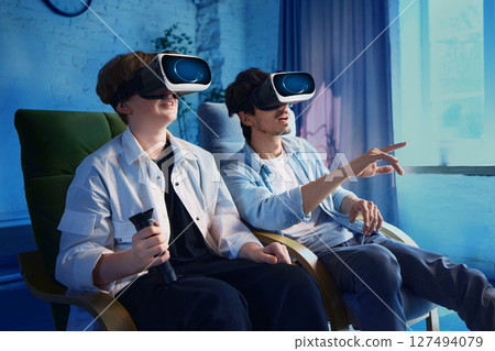 Father and son immersed in virtual reality experience in modern living room setting 127494079