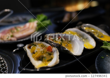 Oysters yellow sauce Silver platter filled with fresh, raw oysters on ice. Three bright yellow lemons are nestled among the oysters 127496341