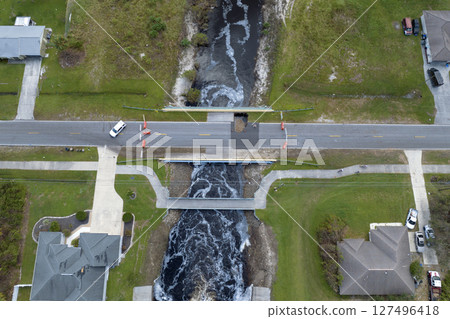Road construction. Law enforcement police blocking car access at destroyed bridge after hurricane flooding water washed away asphalt in Florida. Safety equipment at roadwork site 127496418