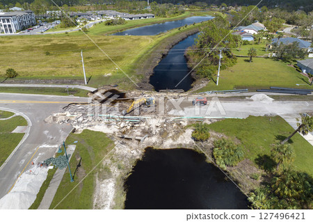 Repair of destroyed bridge after hurricane flood in Florida. Reconstruction of damaged road after flooding water washed away asphalt. Construction equipment at roadwork site Repair of destroyed bridge after hurricane flood in Florida. Reconstruction of damaged road after flooding water washed away asphalt. Construction equipment at roadwork site 127496421