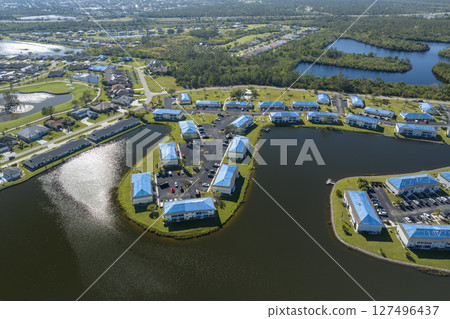 Protective tarp covering rooftop after hurricane damage against rain water leaking until replacement of asphalt shingles on damaged apartment buildings. Aftermath of natural disaster 127496437