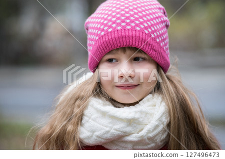Pretty child girl in warm knitted winter clothes outdoors. 127496473